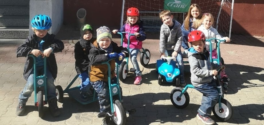 Kinder der KiTa Mäuseburg vor dem Eingang der KiTa auf ihren neuen blauen Rädern.