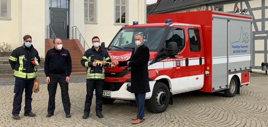 Das neue Feuerwehrauto der Stadt Usingen steht vor der Hugenottenkirche. Herr Bürgermeister Steffen Wernard übergiebt Herrn Andreas Lang den Schlüssel. Links daneben stehen Herr Sven Blecher und Stefan Göttl.