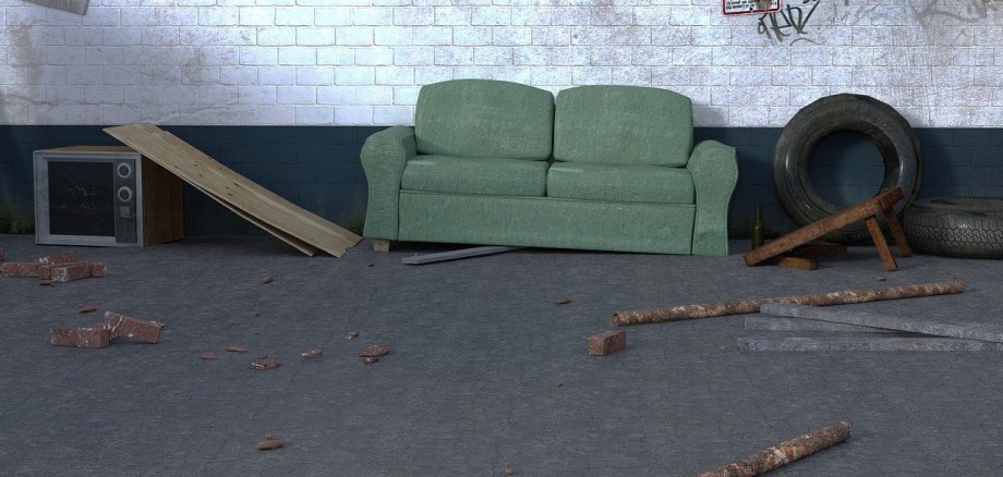 Auf diesem Bild sieht man einen alten Kellerraum mit Sperrmüll (eine alte Couch, Holz, etc.).
