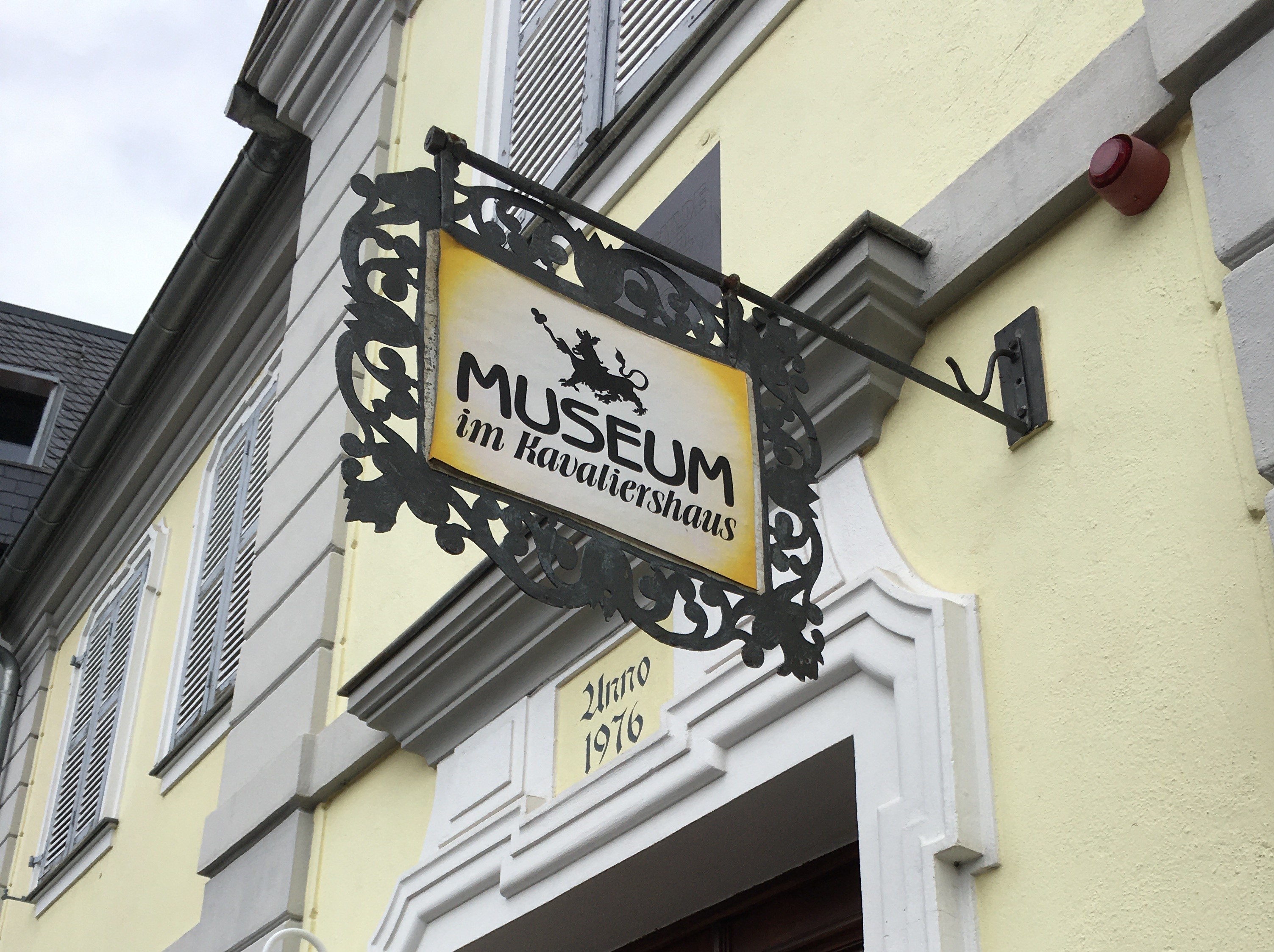 Ein Schild mit der Aufschrift "Museum im Kavaliershaus" hängt an einer gelben Ausenfassade vom Museum.