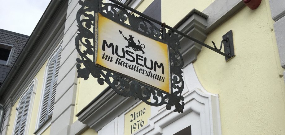 Ein Schild mit der Aufschrift "Museum im Kavaliershaus" hängt an einer gelben Ausenfassade vom Museum.