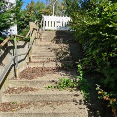 Eine Treppe, die nach oben führt mit einem silbernen Geländer auf der linken Seite.