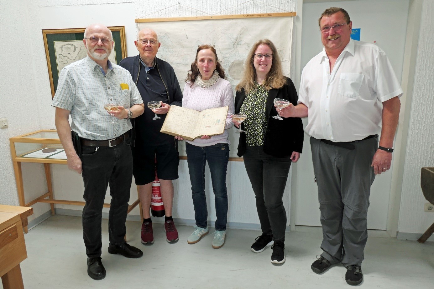 Zu sehen sind Vertreter des Stadtarchivs und des Geschichtsvereins mit einer Vertreterin der Stadtverwaltung und der Restauratorin bei der Übergabe des restaurierten Flurbuchs im Usinger Stadtarchiv.