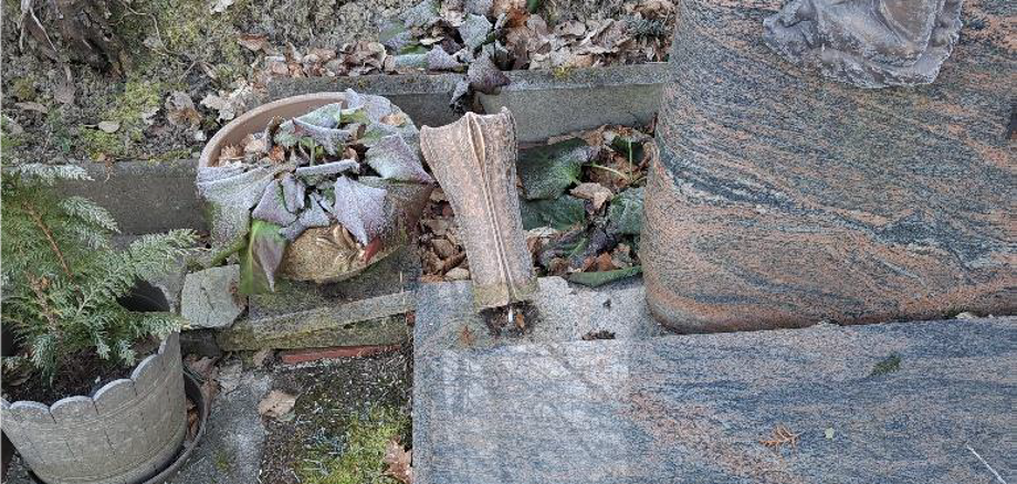 Zerstörte Vase an einem Grabstein.