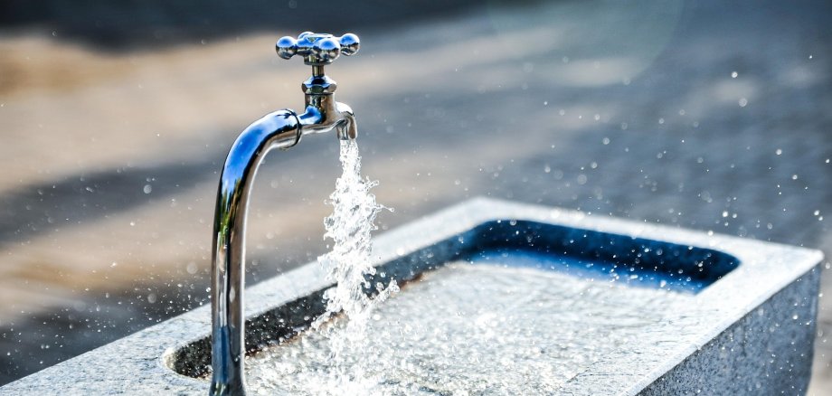 Sprudelnder Wasserhahn in einer Stadtumgebung