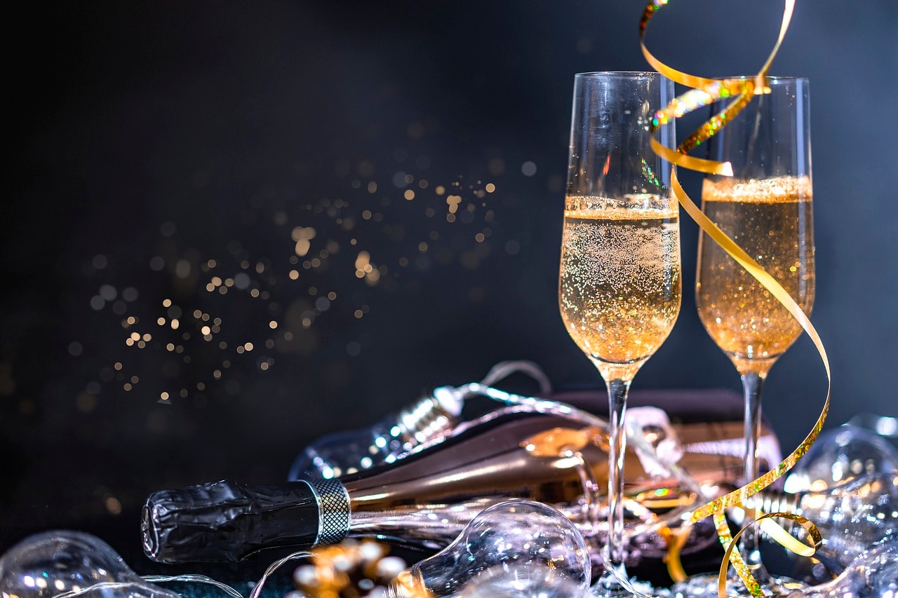Sekt Zwei volle Sektgläser stehen auf goldenen Luftschlangen vor einem dunklen Hintergrund.