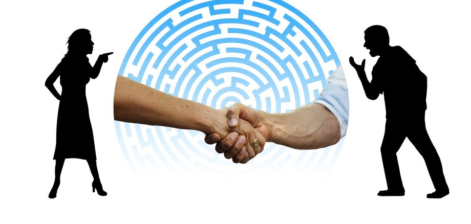 Neuwahl einer stellvertretenden Schiedsperson für den Schiedsamtsbezirk Usingen Links befindet sich eine Frau, welche mit dem Zeigeifnger auf einen rechtsstehenden Mann zeigt. Der Mann hebt seine Hand. Zwischen den beiden Personen sieht man zwei Hände, die sich gegenseit die Hand schütteln.