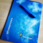 Blaue Bewerbungsmappe auf der ein blauer Kugelschreiber liegt.