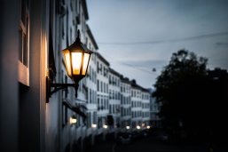 Laterne In der Dämmerung leuchtet eine Laterne an der Hauswand eines Mehrfamilienhauses.